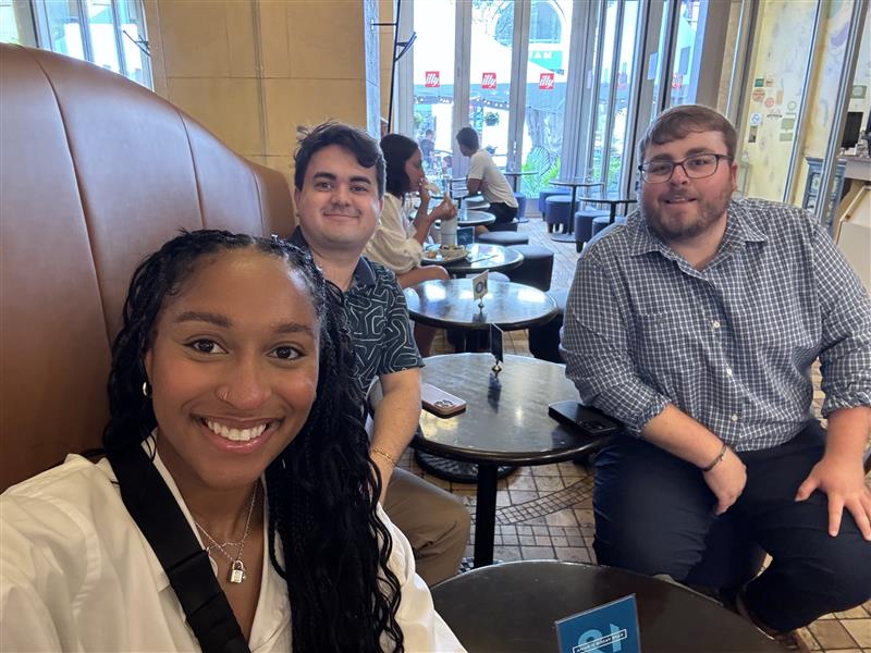3 team members sitting at a table smiling for a selfie
